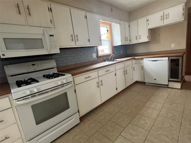 kitchen with sink, white appliances, light tile patterned floors, backsplash, and white cabinets