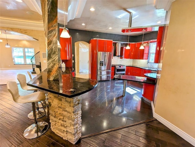 kitchen with appliances with stainless steel finishes, decorative light fixtures, extractor fan, and dark wood-type flooring