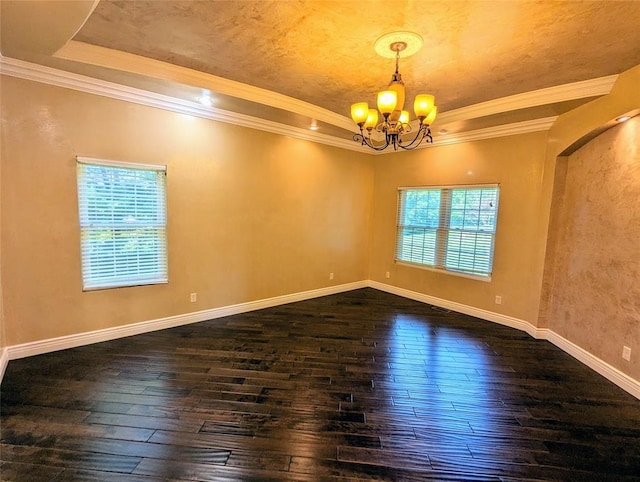 empty room featuring a notable chandelier, dark hardwood / wood-style flooring, a raised ceiling, and crown molding