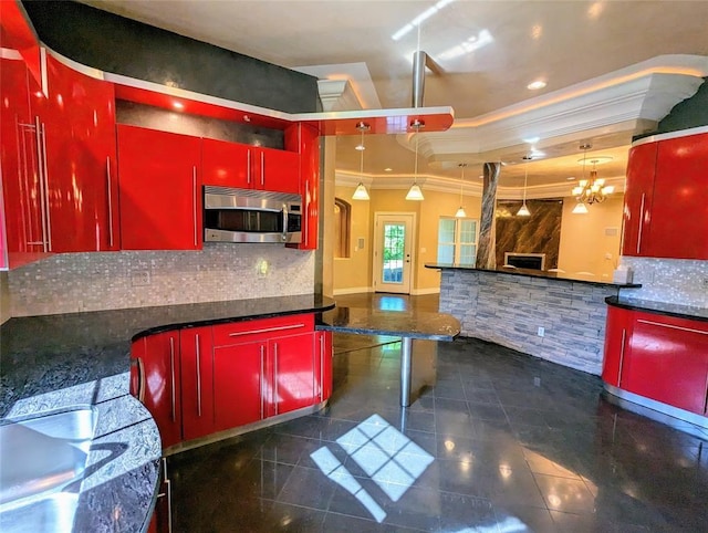 kitchen featuring a fireplace, backsplash, decorative light fixtures, and crown molding