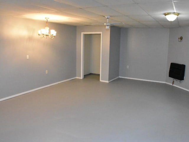 spare room with heating unit, a drop ceiling, concrete flooring, and an inviting chandelier