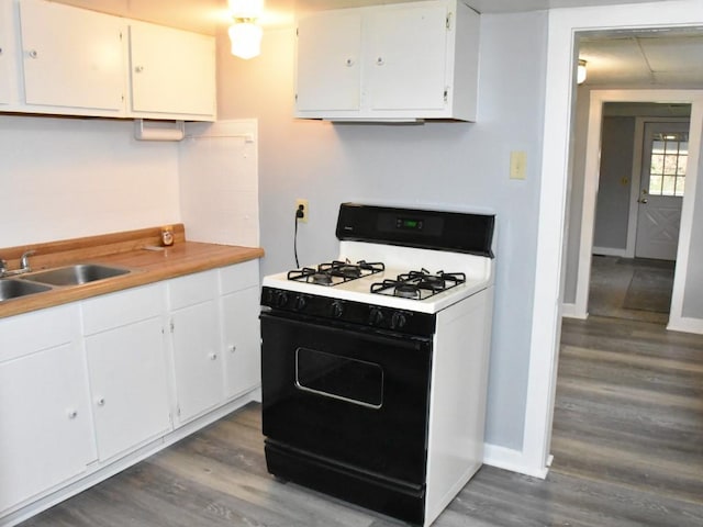 kitchen with white cabinets, white gas range oven, dark hardwood / wood-style floors, and sink