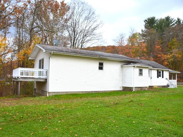 view of side of home with a deck and a lawn