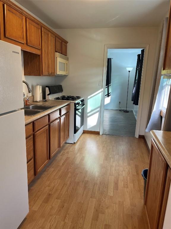 kitchen with sink, white appliances, and light wood-type flooring