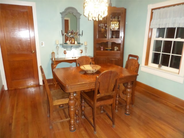 dining space with hardwood / wood-style floors and an inviting chandelier