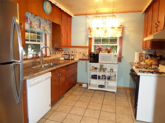 kitchen featuring sink, decorative light fixtures, white appliances, decorative backsplash, and light tile patterned floors