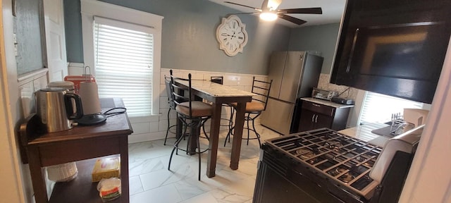 kitchen with ceiling fan, a healthy amount of sunlight, and stainless steel refrigerator