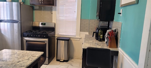 kitchen featuring light stone counters, stainless steel appliances, and tasteful backsplash