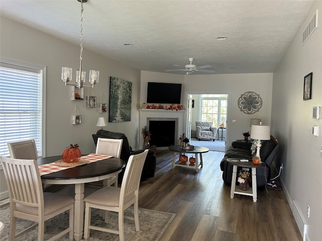 dining space with a textured ceiling, dark hardwood / wood-style flooring, and ceiling fan with notable chandelier