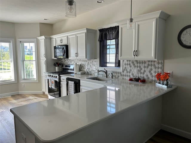 kitchen with sink, kitchen peninsula, pendant lighting, decorative backsplash, and black appliances