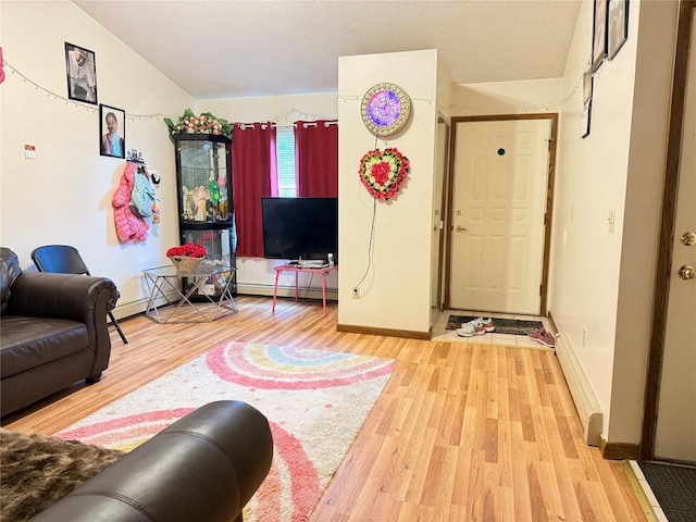 living area featuring a baseboard heating unit, baseboards, vaulted ceiling, and wood finished floors