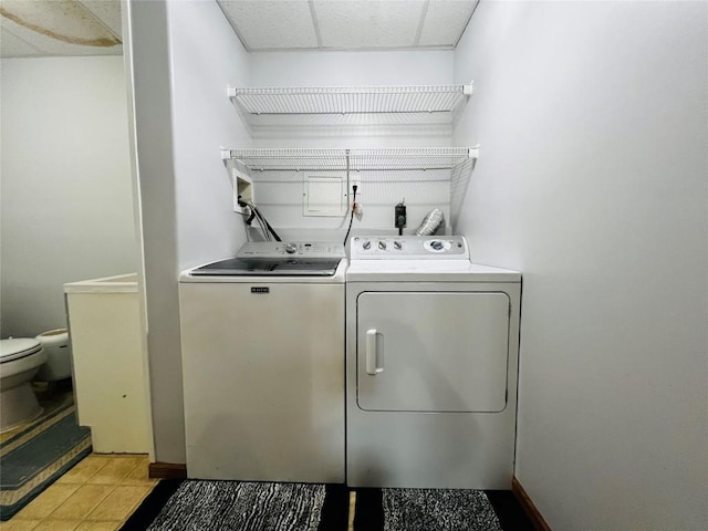 clothes washing area featuring light tile patterned floors and washer and clothes dryer