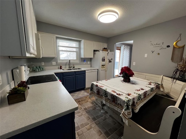 kitchen featuring a wealth of natural light, white appliances, sink, blue cabinetry, and white cabinets