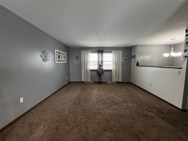 spare room featuring a chandelier and dark colored carpet