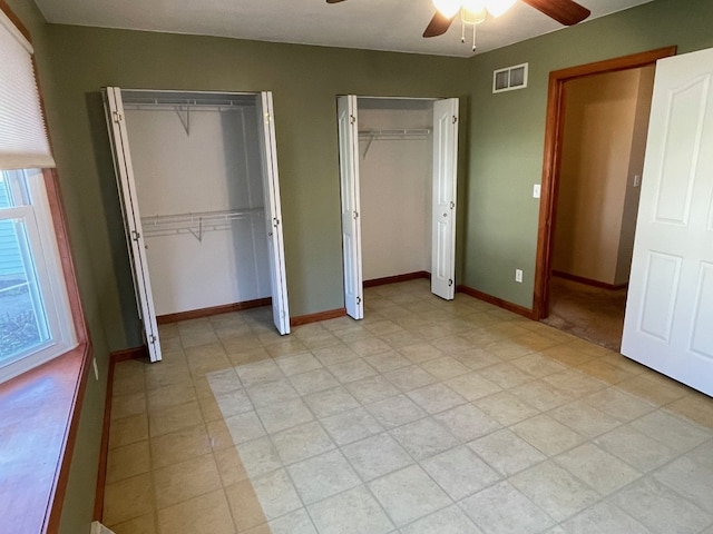 unfurnished bedroom featuring multiple closets and ceiling fan