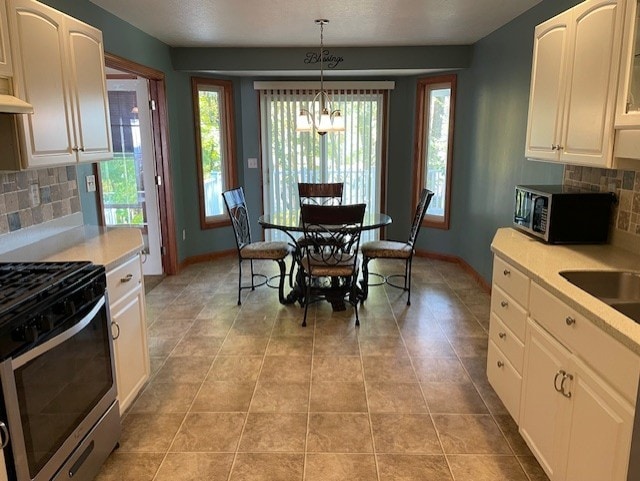 kitchen featuring decorative backsplash, appliances with stainless steel finishes, pendant lighting, white cabinetry, and light tile patterned flooring