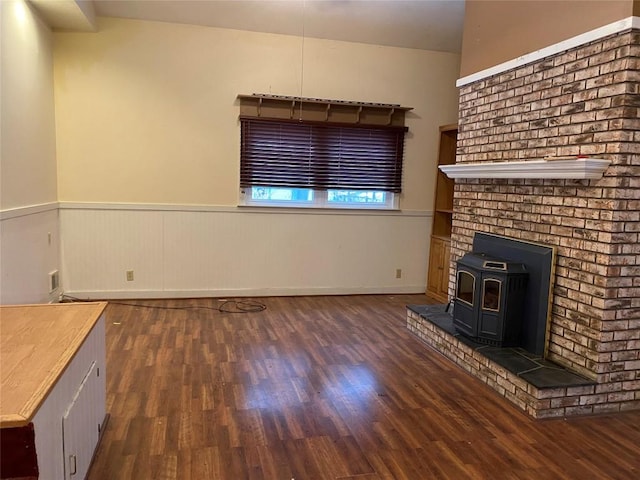 unfurnished living room with a wood stove and dark hardwood / wood-style flooring