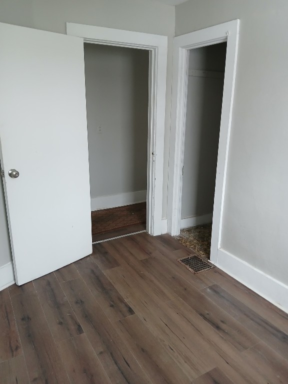 unfurnished bedroom with dark hardwood / wood-style flooring and a closet