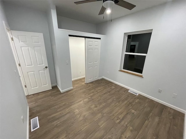 unfurnished bedroom with ceiling fan, a closet, and dark wood-type flooring