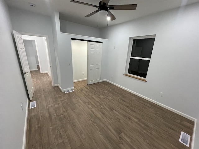 unfurnished bedroom featuring dark hardwood / wood-style flooring, ceiling fan, and a closet