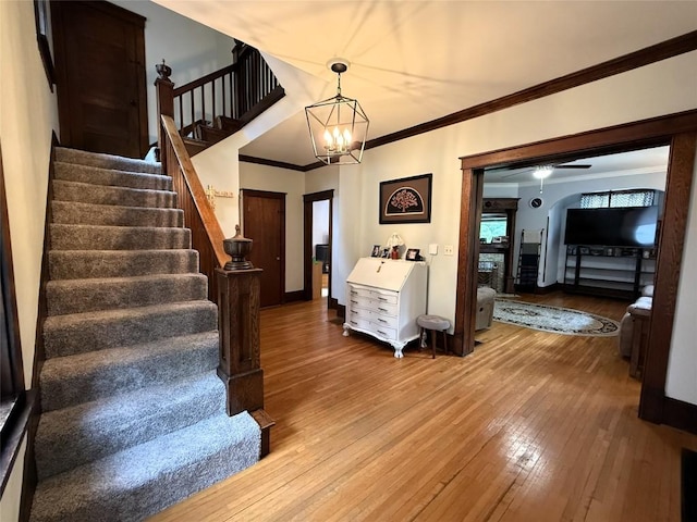 566 Walnut St, Meadville, PA 16335 - staircase with wood-type flooring, crown molding, a chandelier, a fireplace with raised hearth, and ceiling fan