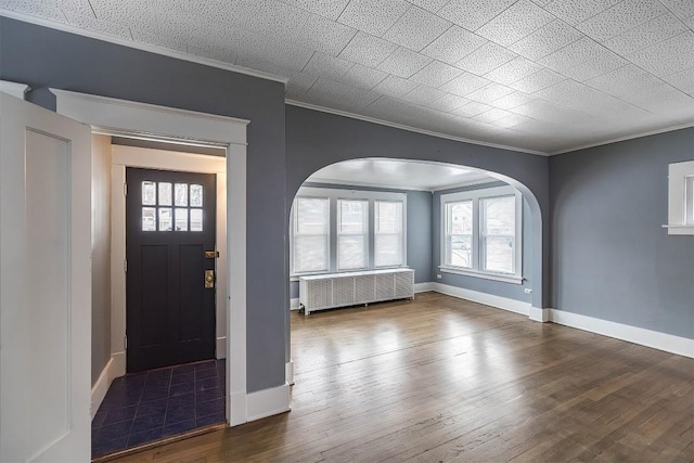 entrance foyer with crown molding, radiator heating unit, and dark wood-type flooring