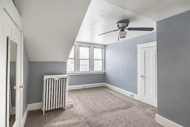 additional living space with radiator, ceiling fan, and carpet