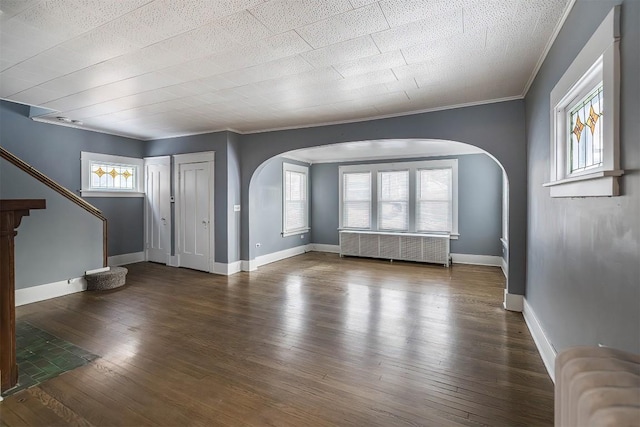 unfurnished living room with radiator, crown molding, and dark hardwood / wood-style floors