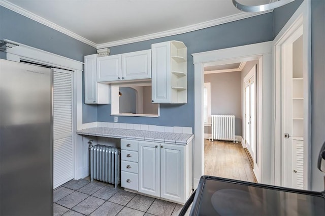 kitchen with white cabinetry, radiator heating unit, and tile counters