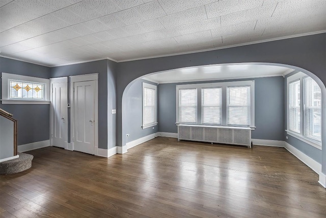 unfurnished living room featuring ornamental molding, radiator heating unit, and wood-type flooring