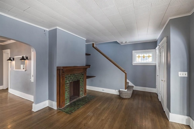 unfurnished living room with ornamental molding, a brick fireplace, and dark hardwood / wood-style flooring