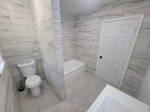 bathroom featuring tile patterned floors, toilet, tile walls, and a tub