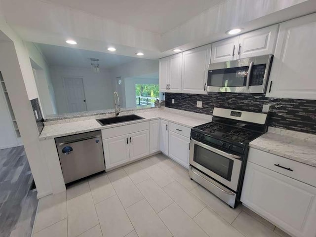 kitchen featuring white cabinetry, sink, light stone counters, and appliances with stainless steel finishes