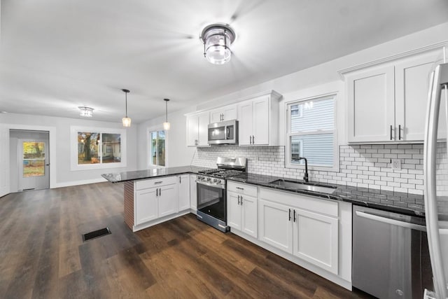 kitchen with sink, kitchen peninsula, decorative light fixtures, white cabinets, and appliances with stainless steel finishes