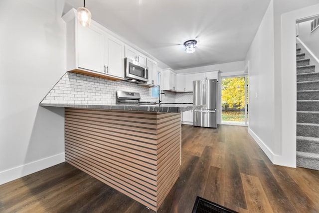 kitchen with backsplash, kitchen peninsula, white cabinetry, and appliances with stainless steel finishes