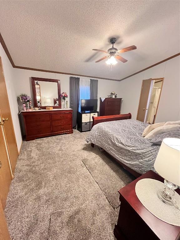 carpeted bedroom with a ceiling fan, ornamental molding, and a textured ceiling
