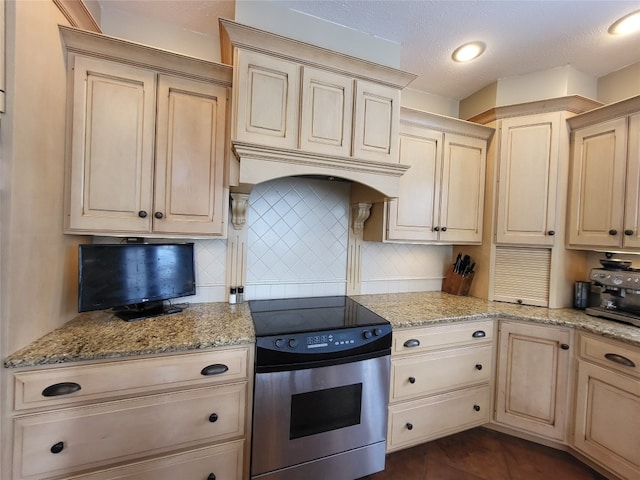 kitchen with electric range, backsplash, and light brown cabinetry