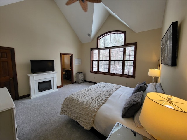 carpeted bedroom with a glass covered fireplace, ceiling fan, baseboards, and high vaulted ceiling