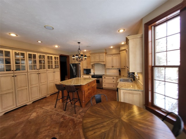 kitchen featuring a kitchen island, a sink, appliances with stainless steel finishes, a kitchen bar, and a notable chandelier