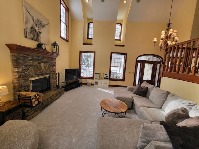 carpeted living room with a notable chandelier, a fireplace, baseboards, and a towering ceiling