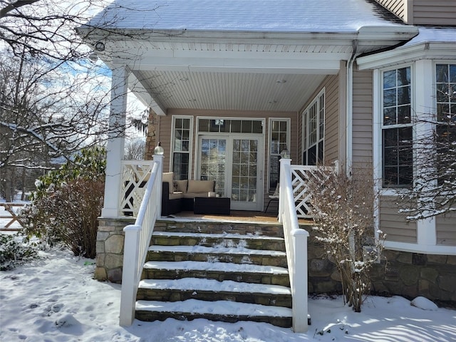 snow covered property entrance with a porch