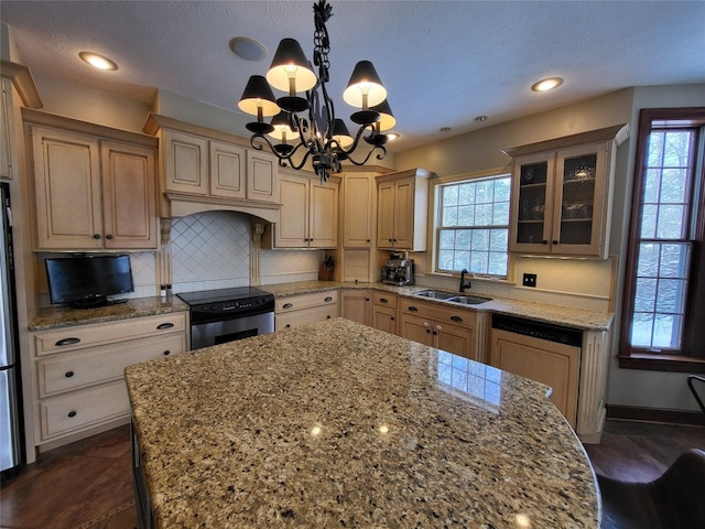 kitchen featuring a sink, paneled dishwasher, electric range oven, an inviting chandelier, and a healthy amount of sunlight