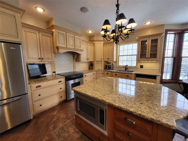 kitchen featuring tasteful backsplash, a healthy amount of sunlight, glass insert cabinets, appliances with stainless steel finishes, and a sink