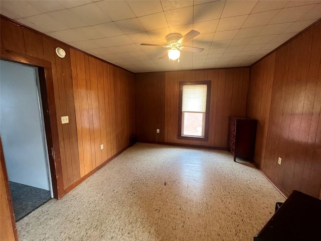 spare room with ceiling fan and wooden walls