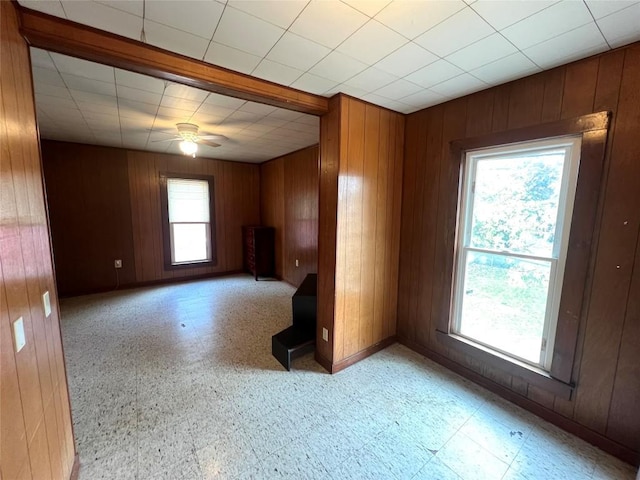 spare room featuring ceiling fan and wood walls