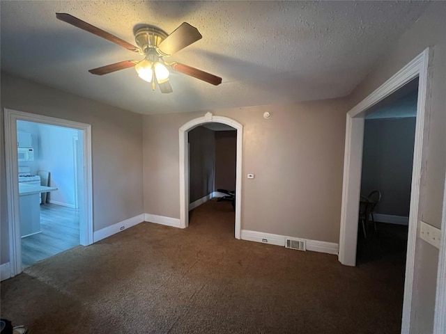 carpeted empty room featuring ceiling fan and a textured ceiling