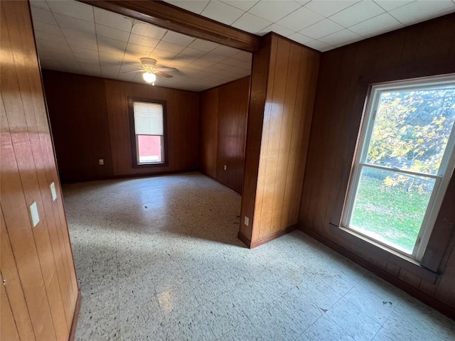 empty room featuring ceiling fan and wooden walls