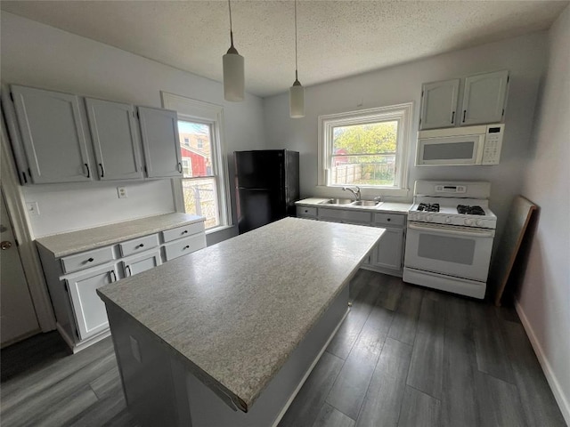 kitchen with decorative light fixtures, plenty of natural light, white appliances, and sink