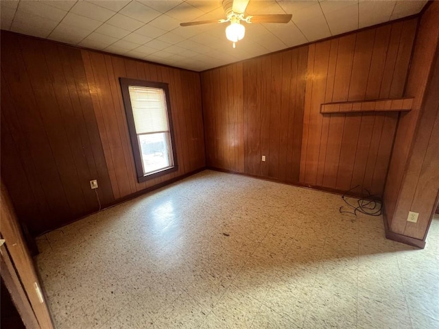 empty room with ceiling fan and wooden walls