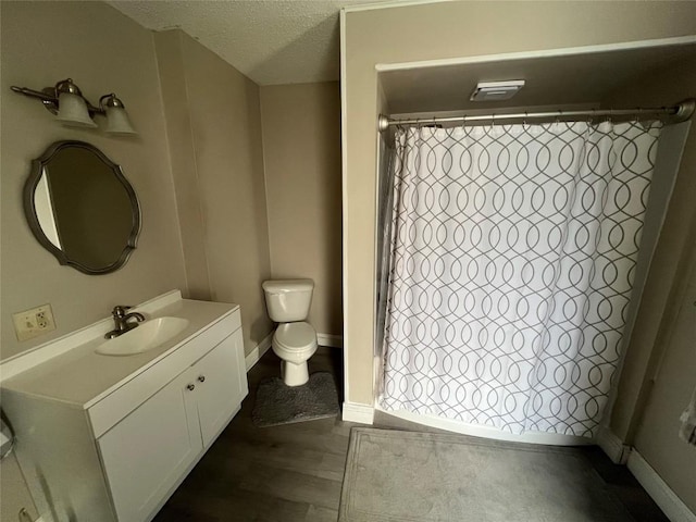 bathroom featuring vanity, toilet, a textured ceiling, and walk in shower